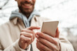 © LIGHTFIELD STUDIOS - cropped view of bearded man pointing with finger at smartphone
