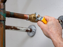 Plumber Turning Water Shut Off Valve. Copper Plumbing Pipe With Brass Water Supply Valve And Yellow Stopcock Handle.