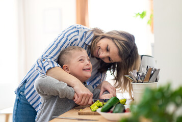 single mother preparing food with down syndrome child at home.