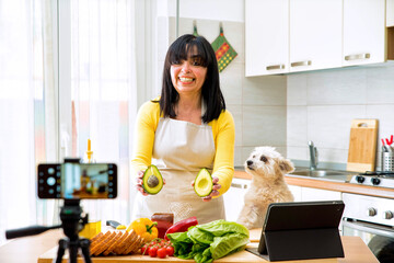 Senior woman cooking healthy food in the kitchen - Food blogger recording video tutorial at home  - People, food and vlogger concept 