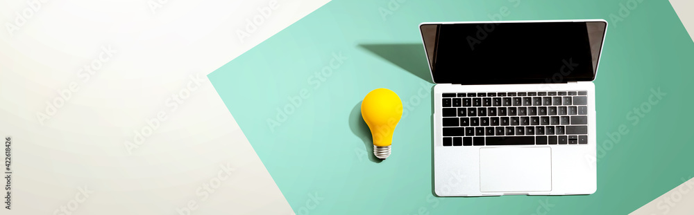 Laptop computer with a yellow light bulb - obrazy, fototapety, plakaty 