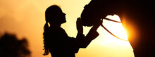 A Horse Rider Girl Stroking The Head Of A Horse In The Rays Of The Setting Sun. Silhouette Of A Girl And A Horse 