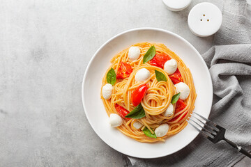 Poster - A portion of spaghetti with tomatoes, mozzarella and basil leaves. Copy space. Light grey background.