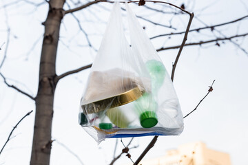 Wall Mural - plastic bottles and tin in cellophane bag on tree, ecology concept