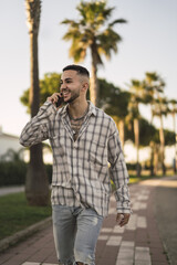 Sticker - Vertical shot of a handsome European man in a plaid shirt talking on the phone and laughing