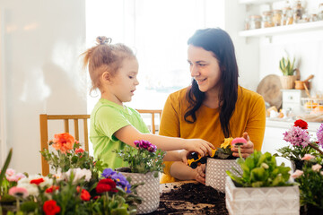 Little helper assists mother while planting flowers at home