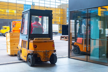 Old loader at work. Loading truck takes boxes out of warehouse. Concept - working as a driver of a loading and unloading vehicle. Man runs warehouse machine. Forklift rear view. Work at forklift.