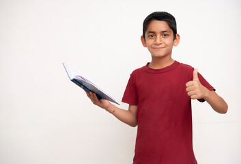 Young indian kid standing on a white isolated background with a book in his hands. Education and fun concept.