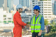 © Mongkolchon - chief engineer and electrician having shandshake together after finished working at construction site in city