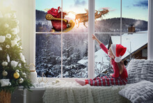 Cute Little Girl On Window Sill At Home Waiting For Santa Claus. Christmas Celebration
