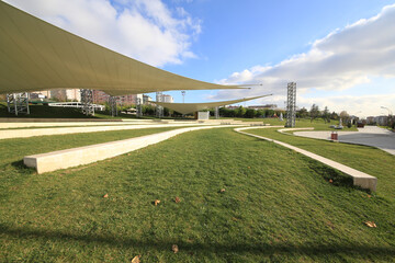 front view, empty activity and parking space with grass floor. Large horizontal awnings protecting from rain and sun. open space for concert and theater