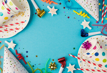 Top view photo of birthday party table composition spiral candles ribbon star pipes striped straws hats sequins polka dots paper cups and plates on isolated blue background with copyspace