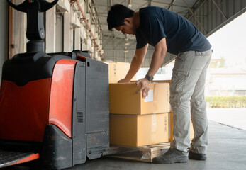 Wall Mural - Asian Warehouse Worker Lifting Card Board Boxes on Pallet. Warehouse. Storage. Cargo Shipment Boxes.