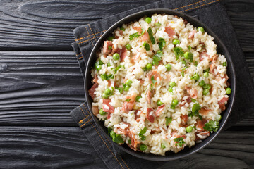 Canvas Print - Arborio rice with green peas and prosciutto Italian risotto close-up in a plate on the table. horizontal top view above