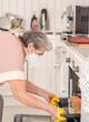 © Ermolaev Alexandr - Senior woman wearing protctive face mask cooks in the kitchen at home