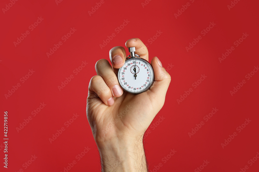 Man holding vintage timer on red background, closeup - obrazy, fototapety, plakaty 
