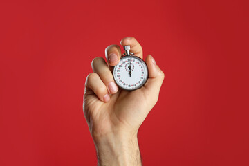 man holding vintage timer on red background, closeup