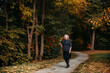 © Natallia Kislitskaya - A happy elderly woman walks along the path in the autumn park. She is beautifully dressed, smiling while enjoying the walk and holding a sprig of leaves in her hand.