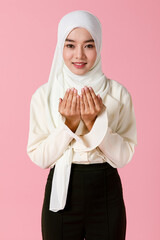 Wall Mural - Portrait of young and cute Asian Islamic woman rise hands in praying gesture in calm and concentrate manner.