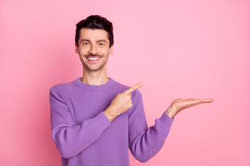 Poster - Portrait of attractive confident cheerful guy holding on palm demonstrating copy space isolated over pink pastel color background