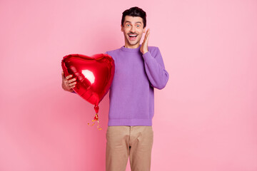 Poster - Photo of excited charming young man dressed purple pullover getting heart balloon arm cheek isolated pink color background