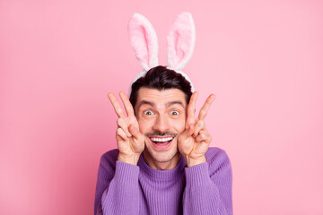 Sticker - Photo of charming funky young man dressed purple pullover rabbit ears showing v-signs cheeks isolated pink color background