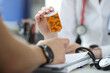 Doctor holding jar of medicines in front of patient closeup