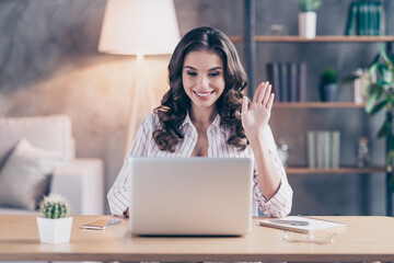 Wall Mural - Photo of sweet friendly young lady wear white shirt waving arm talking modern gadget sitting table indoors inside room home