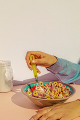 Arm of woman eating colors cereals with milk at vintage kitchen