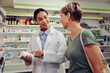 © StratfordProductions - Happy pharmacist giving medicine bottle to female customer in pharmacy