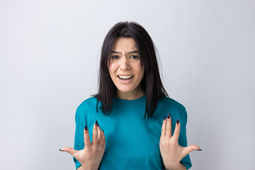 Young beautiful woman with facial expression of surprise standing over gray background.