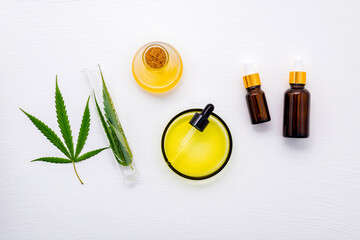 Wall Mural - Glass bottle of cannabis oil and hemp leaves set up  on white background.