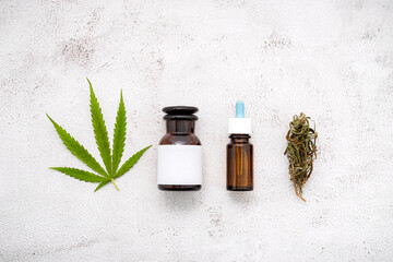 Wall Mural - Glass bottle of cannabis oil with white mortar and hemp leaves set up  on concrete background.