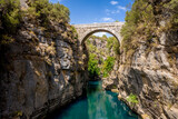 Ancient arch bridge Oluk over the Koprucay river gorge in Koprulu national Park in Turkey. Panoramic scenic view of the canyon and blue stormy mountain river