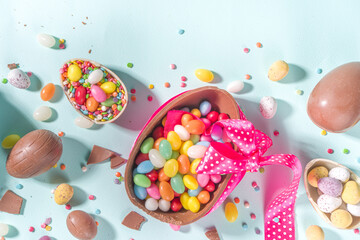 Wall Mural - Various Easter Colorful Sweets and Chocolate Eggs flatlay on light blue background top view copy space