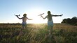 © zoteva87 - Silhouette of children playing on an airplane on a flower field. Dreams of flying. Happy childhood. Two girls play with a toy plane at sunset. Children on background of sun with an airplane in hand.