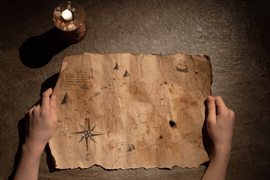 Wall Mural - old treasure map in hands, burning candle, concept of travel, adventure, search for pirate treasure
