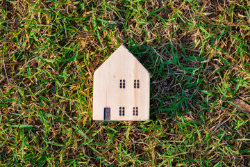 Wall Mural - Wooden toy house model on green grass new home