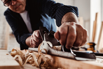 Wall Mural - Carpenter's hands planing a plank of wood with a hand plane