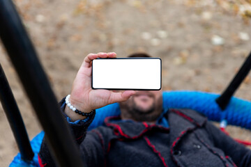 Man taking selfie with smartphone. Blank white screen for copy space