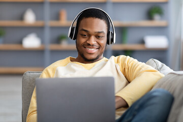 Closeup of happy black guy playing video games on laptop