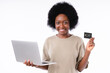 Happy african teenager holding credit card and laptop isolated over white background
