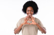 Cheerful african girl showing heart gesture isolated over white background