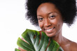 Smiling afro young girl shirtless holding tropical leaf isolated in white background