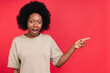 © InsideCreativeHouse - Surprised african teen girl pointing at copy space isolated in red background