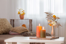 Burning Candles With Autumn Decor On White Table At Home