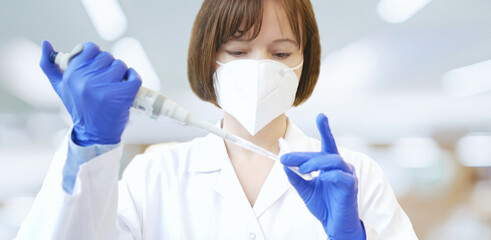 scientist or laboratory researcher in a protective mask and laboratory gloves holds a laboratory pip