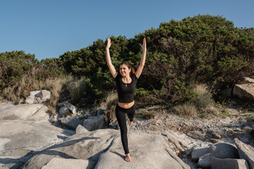 Fitness woman doing stretching exercises at the beach with natural landscape on background.