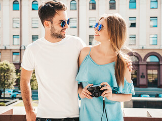 Portrait of smiling beautiful woman and her handsome boyfriend. Woman in casual summer jeans dress. Happy cheerful family. Female having fun. Couple posing on the street background in sunglasses