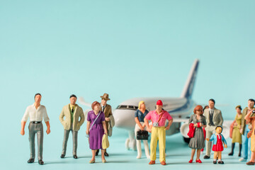 Miniature people stand in a makeshift queue next to the plane. Travel concept